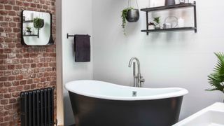 renovating a bathroom black rolltop bath and exposed brick wall