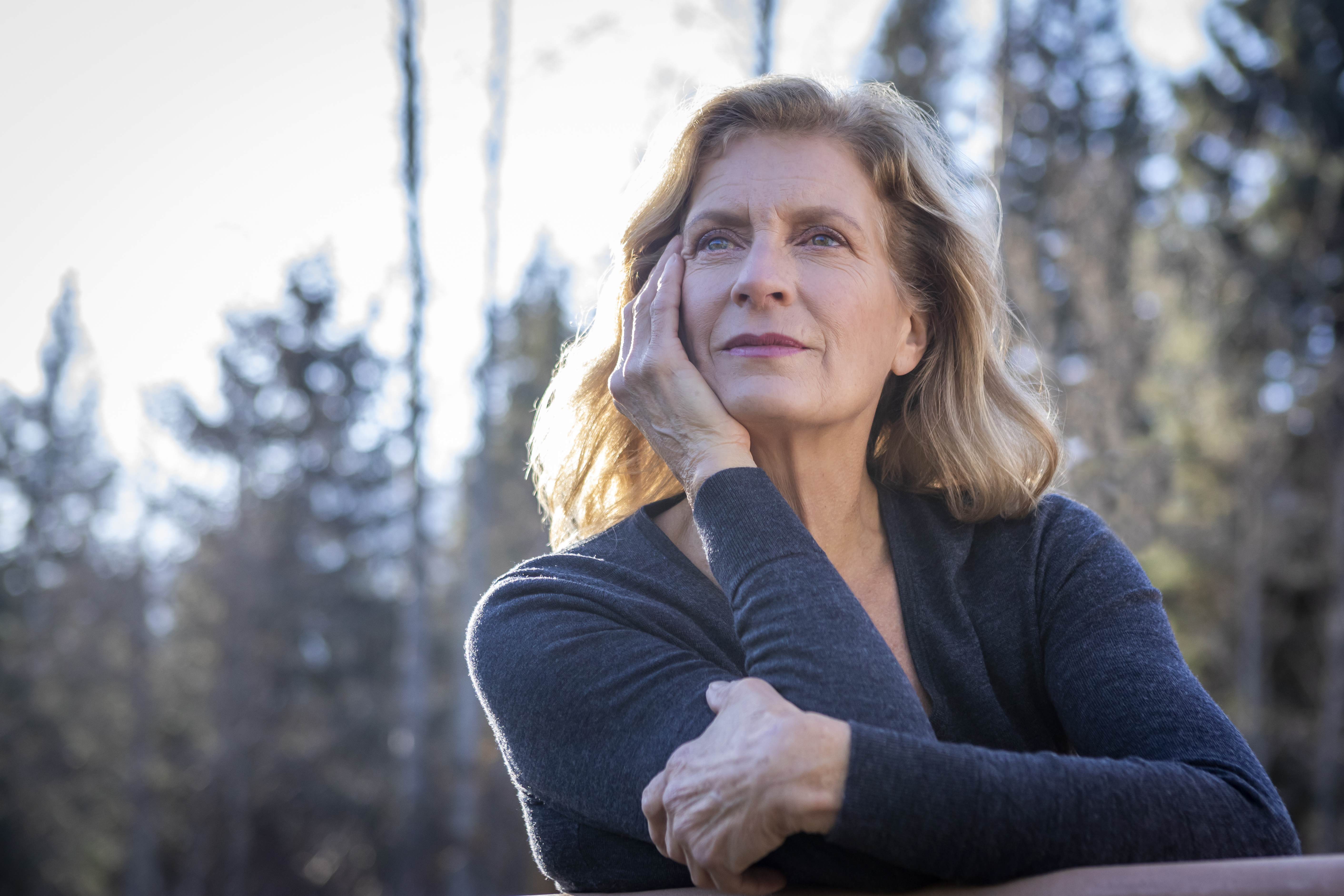 Backlit headshot of mature woman with blond hair.