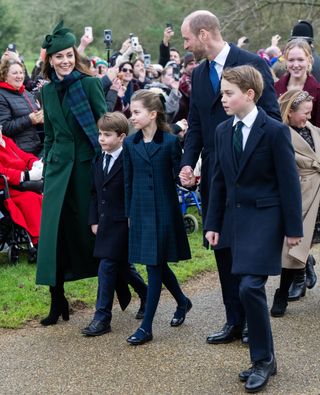 Prince George, Princess Charlotte and Prince Louis wearing blue coats and ties walking outside church with Princess Kate, dressed in a green coat and plaid scarf, and Prince William, in a blue suit, on Christmas Day 2024