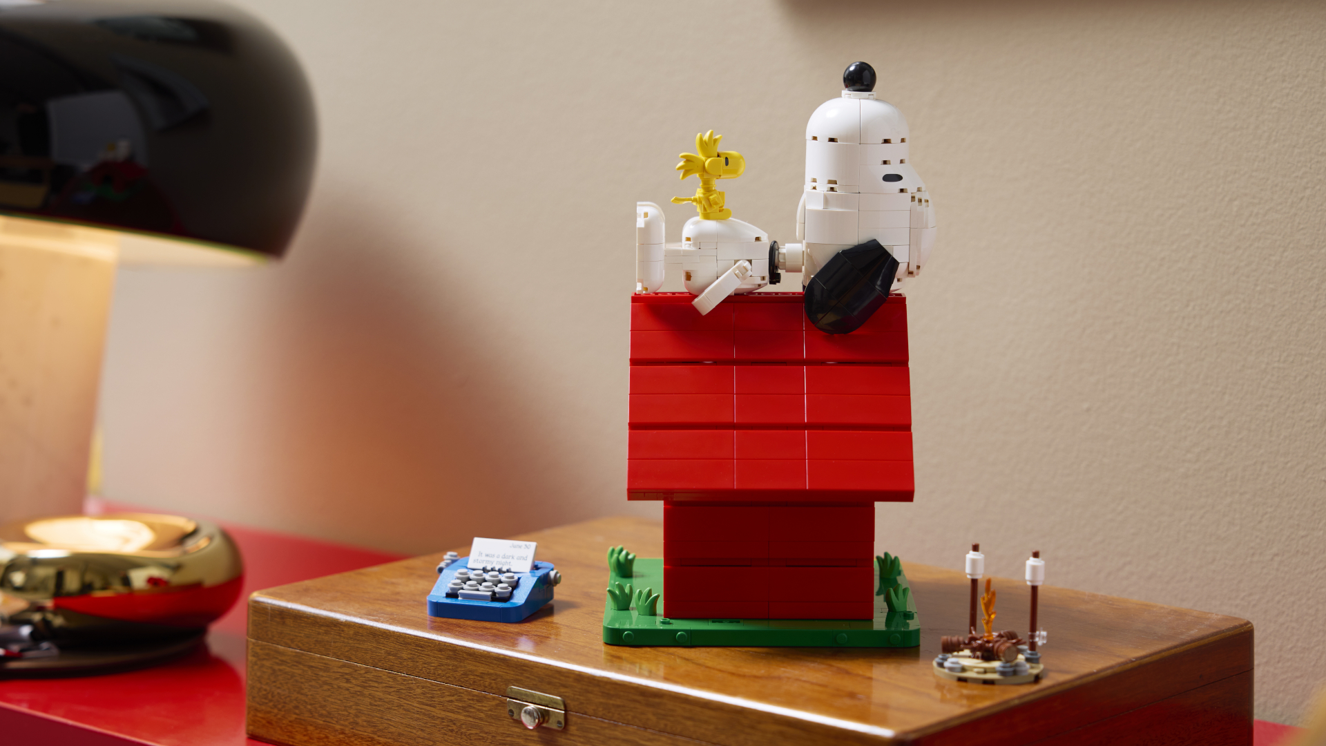 Lego Snoopy lies back on his doghouse with Woodstock the bird sitting on his stomach
