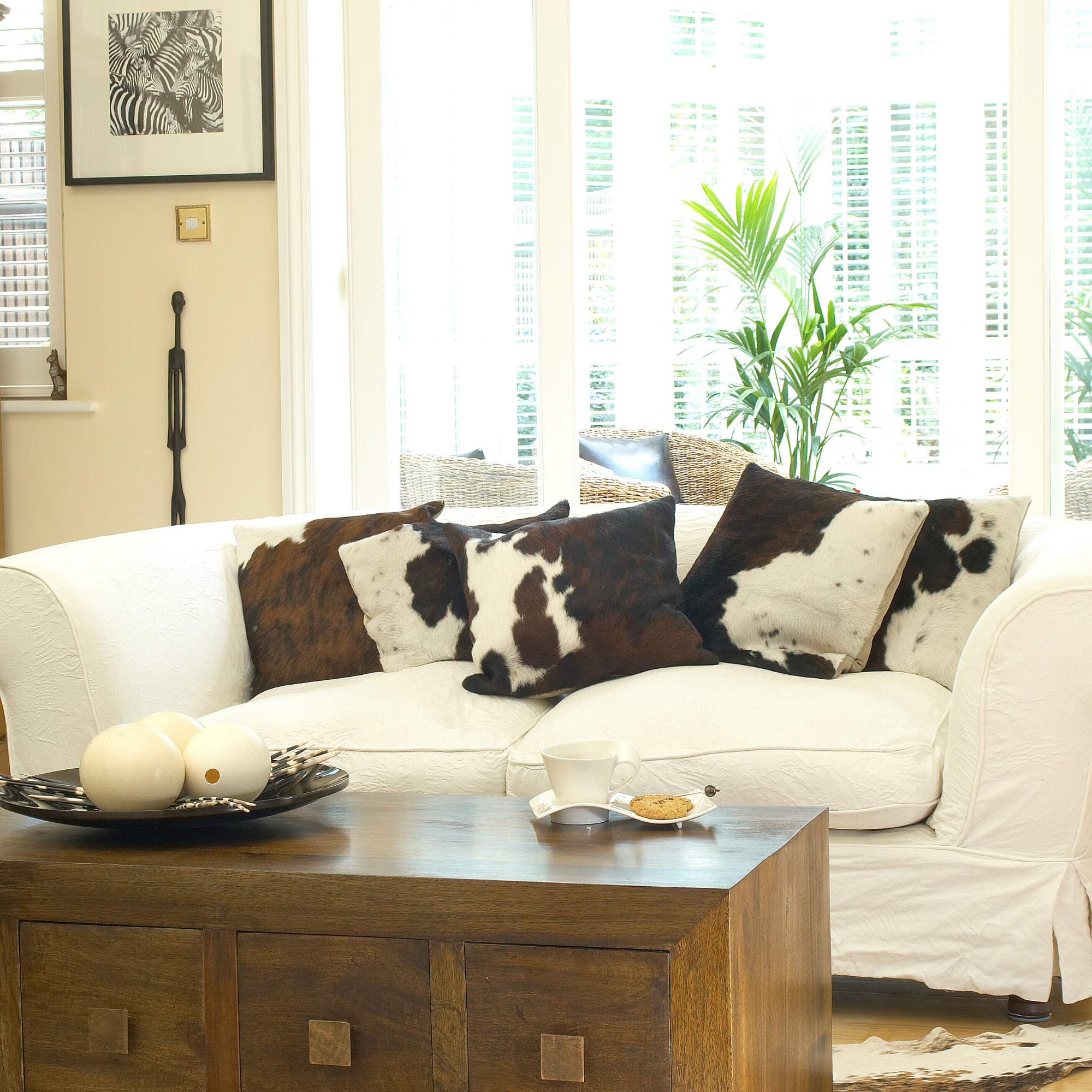 living room, white sofa, cow print cushions, dark wooden coffee table, chest of drawers, french doors to conservatory.