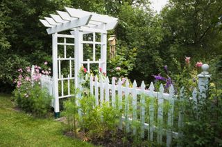 garden arbor ideas: white structure with picket fence and windchimes