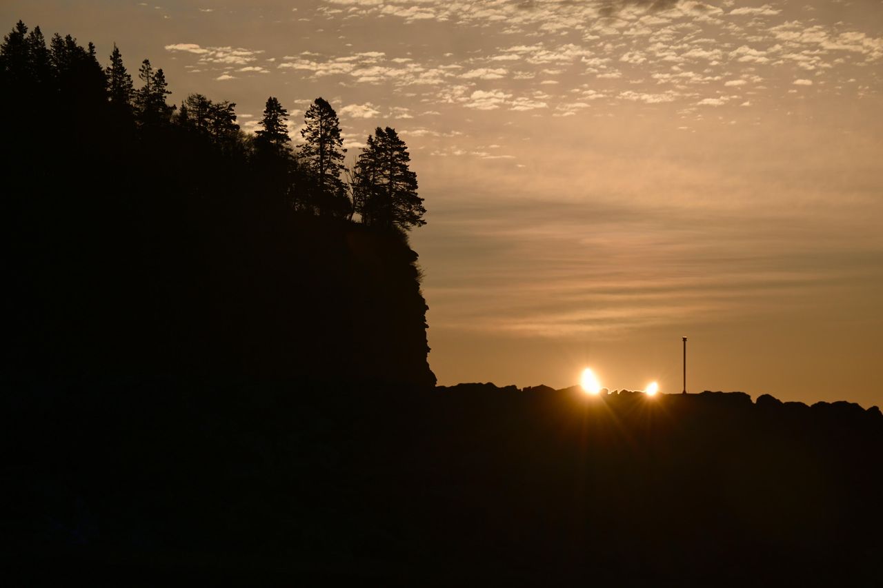 a partially eclipsed sun appears as a crescent shape and rising above the horizon at sunrise.