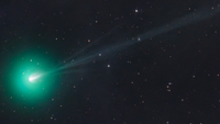 A green comet on a black backdrop with stars. 