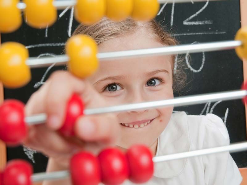 A young girl plays with an abacus in math class. 