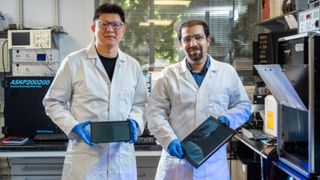 Two researchers holding a panel of their solar cells optimised for indoor light.