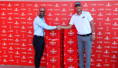 Ugo Coussaud shakes hands with a man whilst stood next to several crates of beer