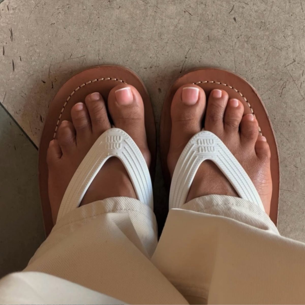 A photo of feet in Miu Miu flip flops