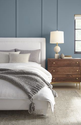 A bedroom with panelled walls painted a smoky blue shade