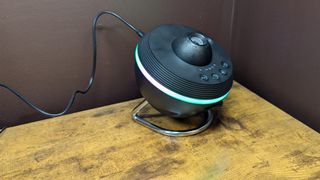 Ainael Meteor and Galaxy Projector on a wooden table against a brown wall