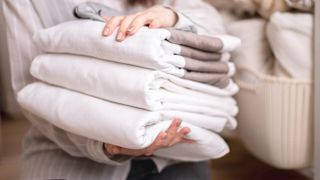 Woman carrying a pile of white bedding