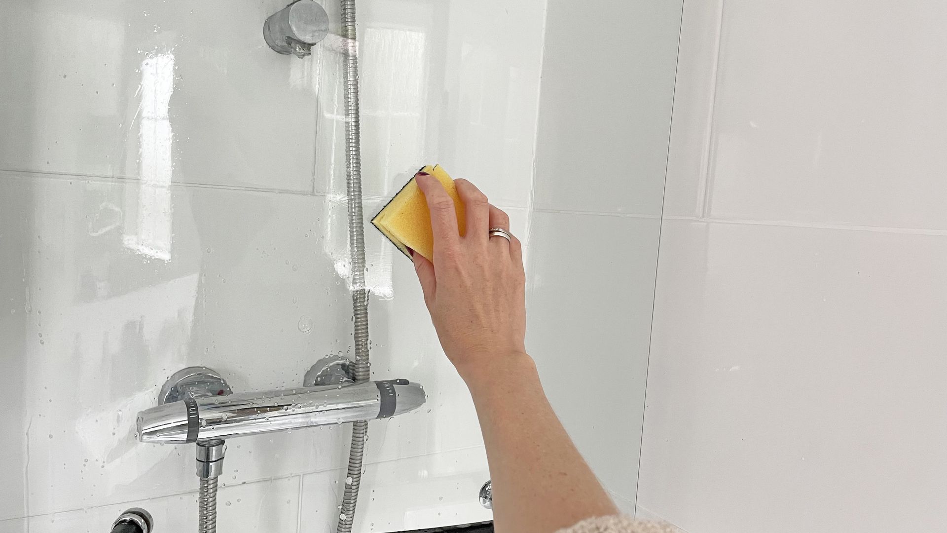 Glass shower door being scrubbed as a stage of how to clean a glass shower door