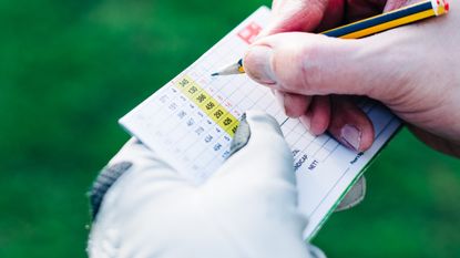 Close-up of a player marking his scorecard