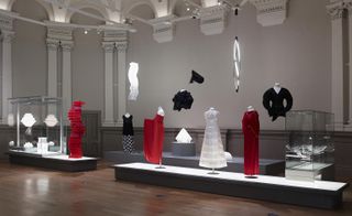 Modern Japanese design pieces in red, black and white on display in an art gallery, featuring costume designs, lighting and craft designs.
