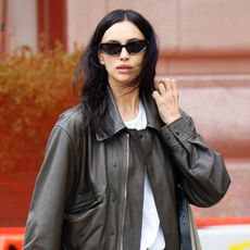 Irina Shayk wearing a leather bomber jacket, white T-shirt, ripped jeans, and white Adidas Samba sneakers in NYC