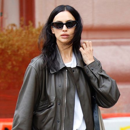 Irina Shayk wearing a leather bomber jacket, white T-shirt, ripped jeans, and white Adidas Samba sneakers in NYC