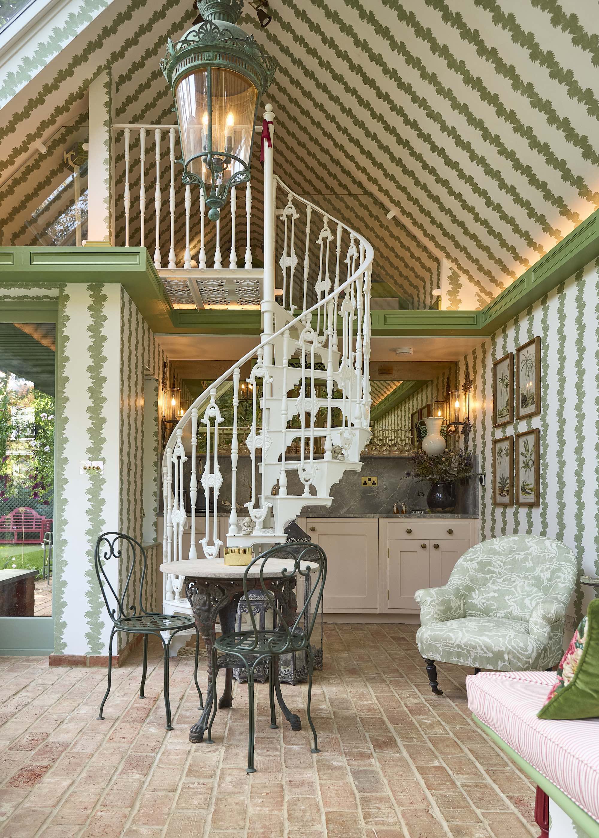 cast iron spiral staircase in garden room with green striped wallpaper and terracotta floors