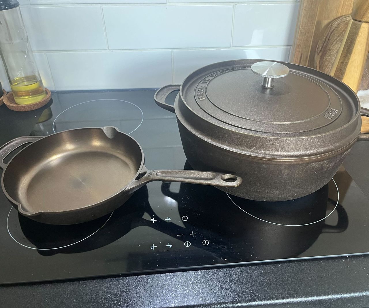 A cast iron mini skillet and Dutch oven on a black glass stove.
