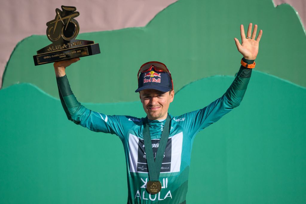 Team Q36.5 Pro Cycling Team British rider Tom Pidcock celebrates with his trophy on the podium after winning the overall AlUla Tour cycling race, after the fifth stage of the race from AlUla Camel Cup track to AlUla Camel Cup track on February 1, 2025. (Photo by Loic VENANCE / AFP)