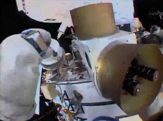 A Russian spacewalkers tightens screws on a loose antenna cover outside the International Space Station on Aug. 22, 2013 in this still from a helmet camera video view.