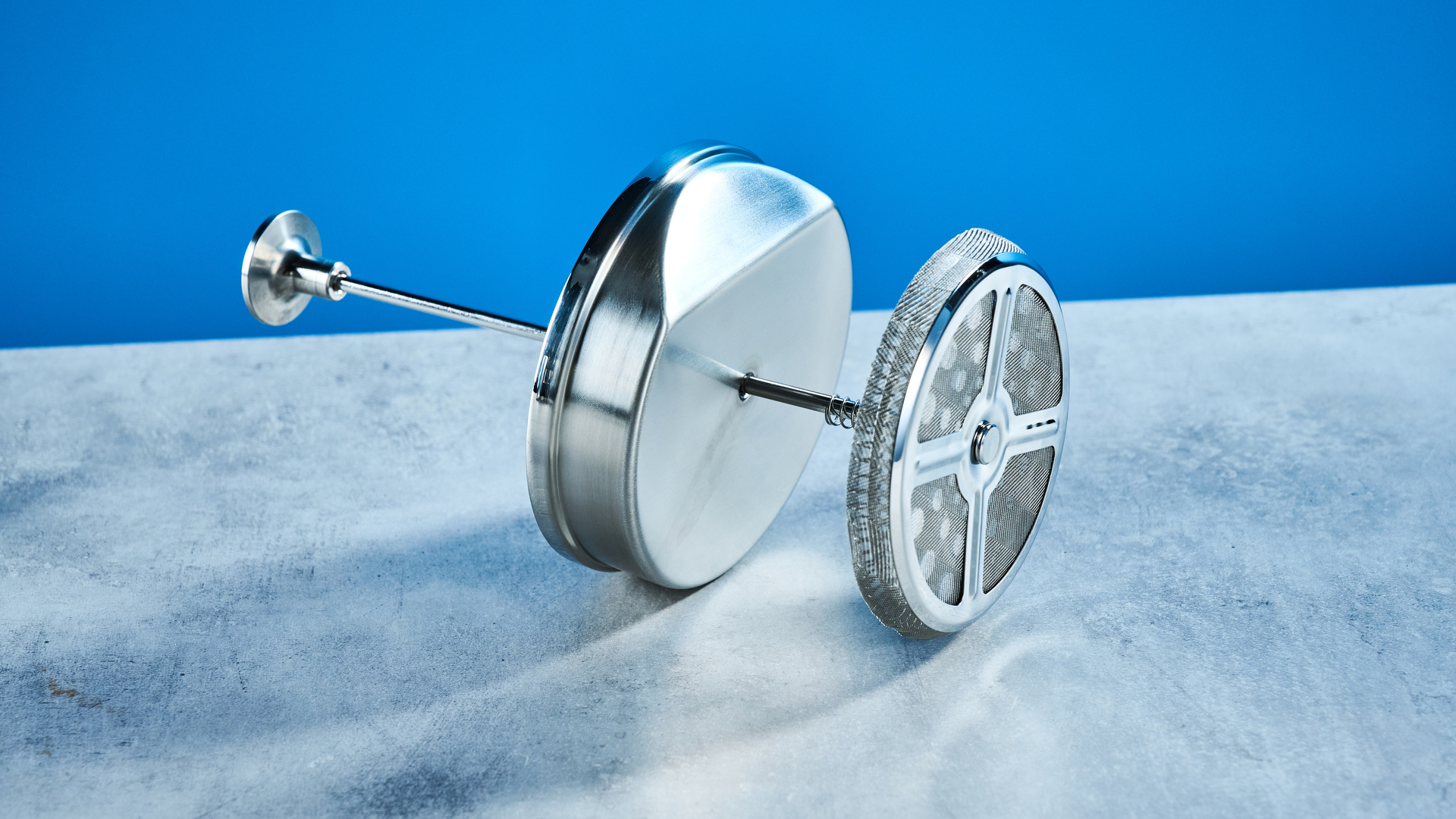 the aarke french press in silver showing the french press filter system, lid, spout, and inside photographed against the blue tom's guide background