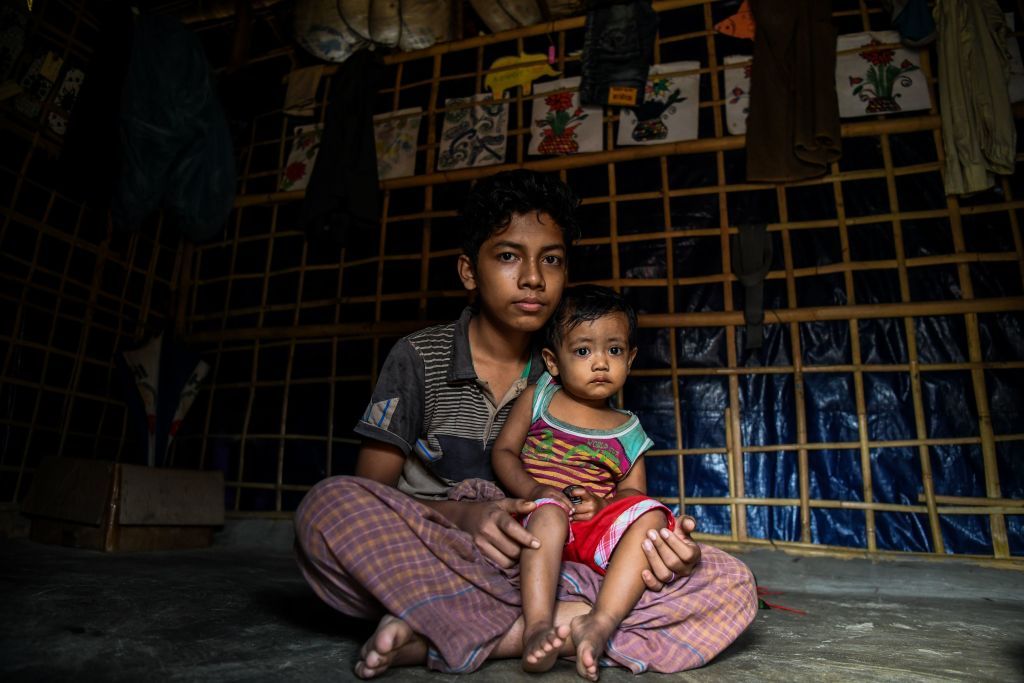 Rohingya refugee boy Kamal Sadiq, 14, holds his cousin Ruma Sadiq inside his home at the Kutupalong camp in Ukhia near Cox&amp;#039;s Bazar on August 13, 2018.