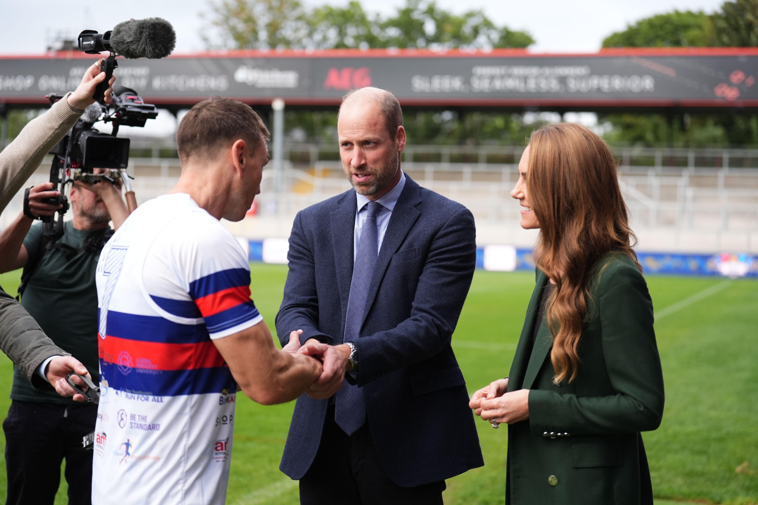 Princess Kate and Prince William talking to Kevin Sinfield with a camera man behind them