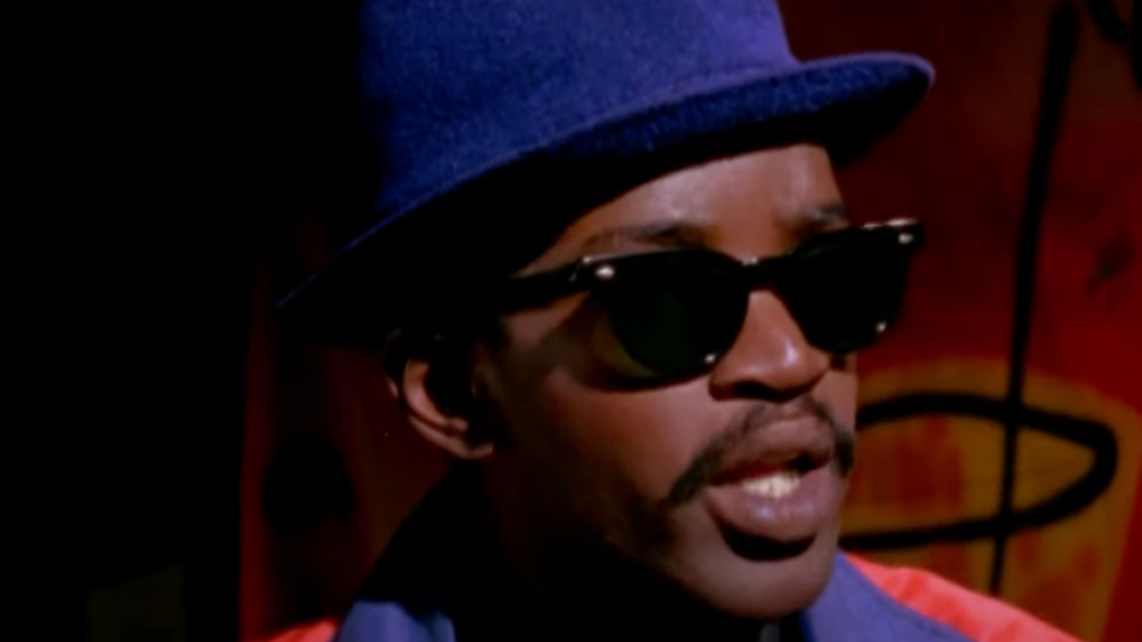 Fab Five Freddie wearing a blue hat and sunglasses in Wild Style