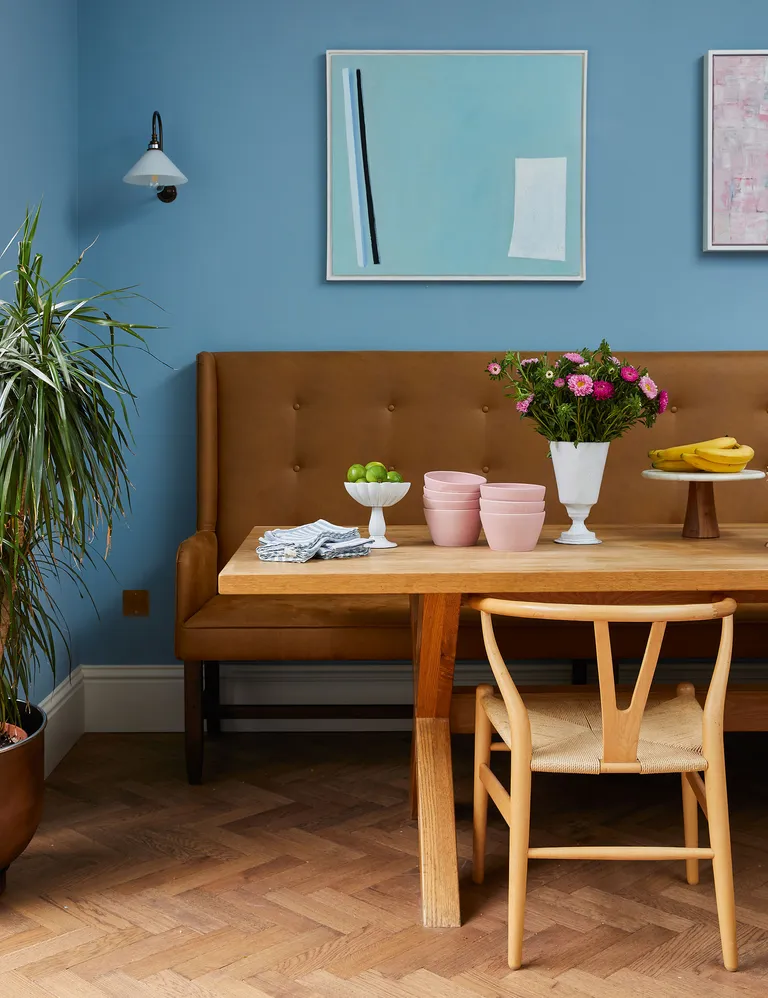 Blue dining room with brown bench seating and wood table