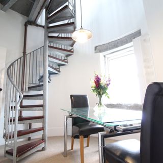 light house dining area with dining table and chairs and spiral staircase