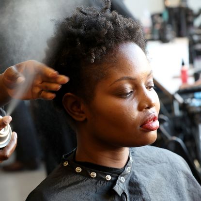 a model having her hair hairsprayed backstage at fashion week