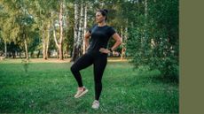 Woman doing standing ab exercises in park wearing activewear