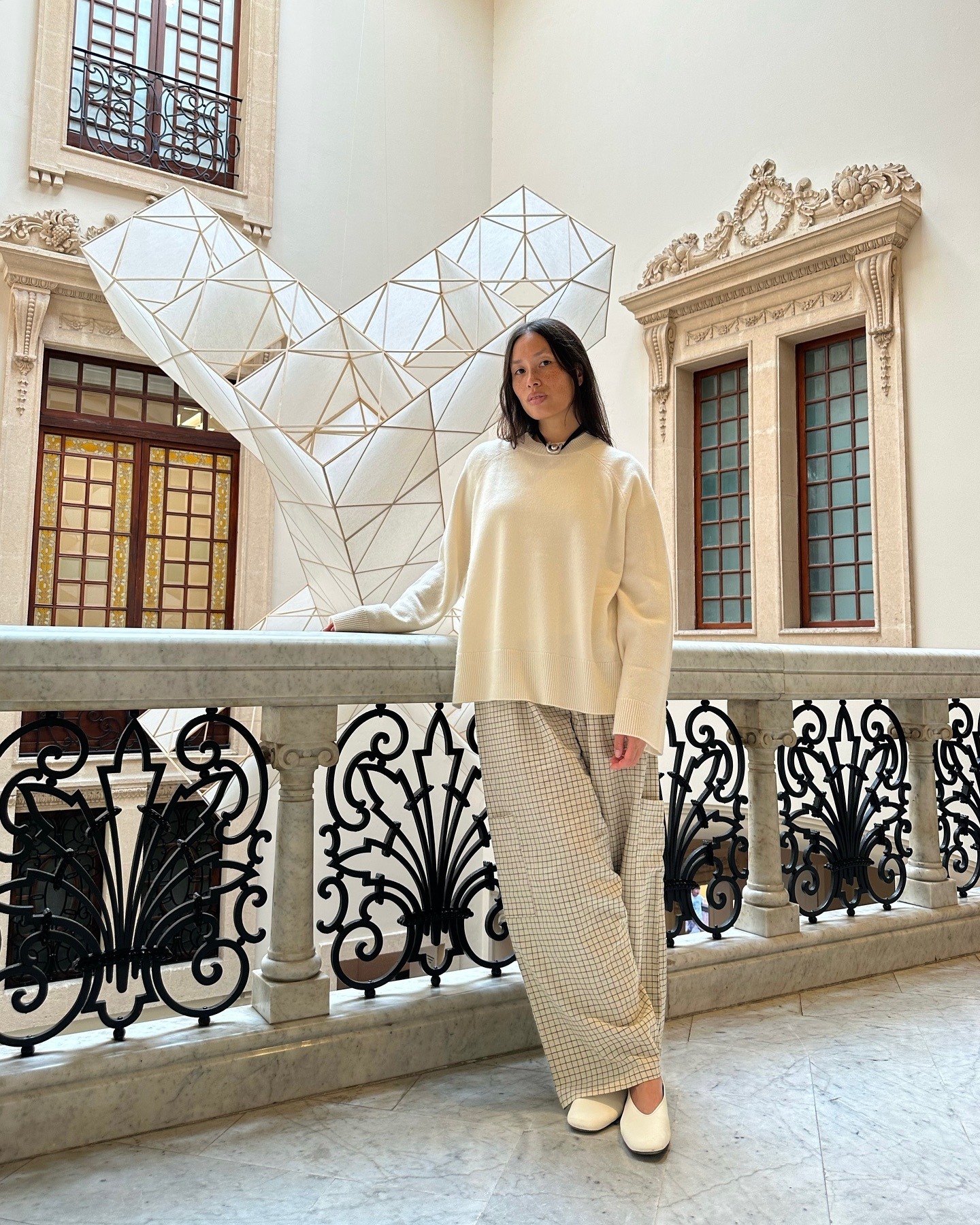 Influencer @vikilefevre wears a white jumper with gingham trousers and white leather ballet pumps.