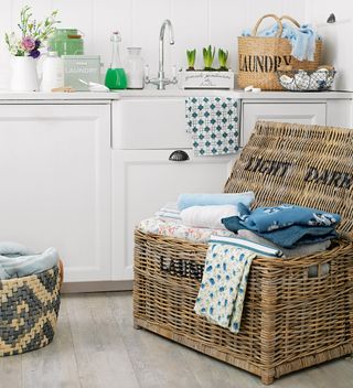White laundry room with 2 laundry baskets with laundry on the wooden floor