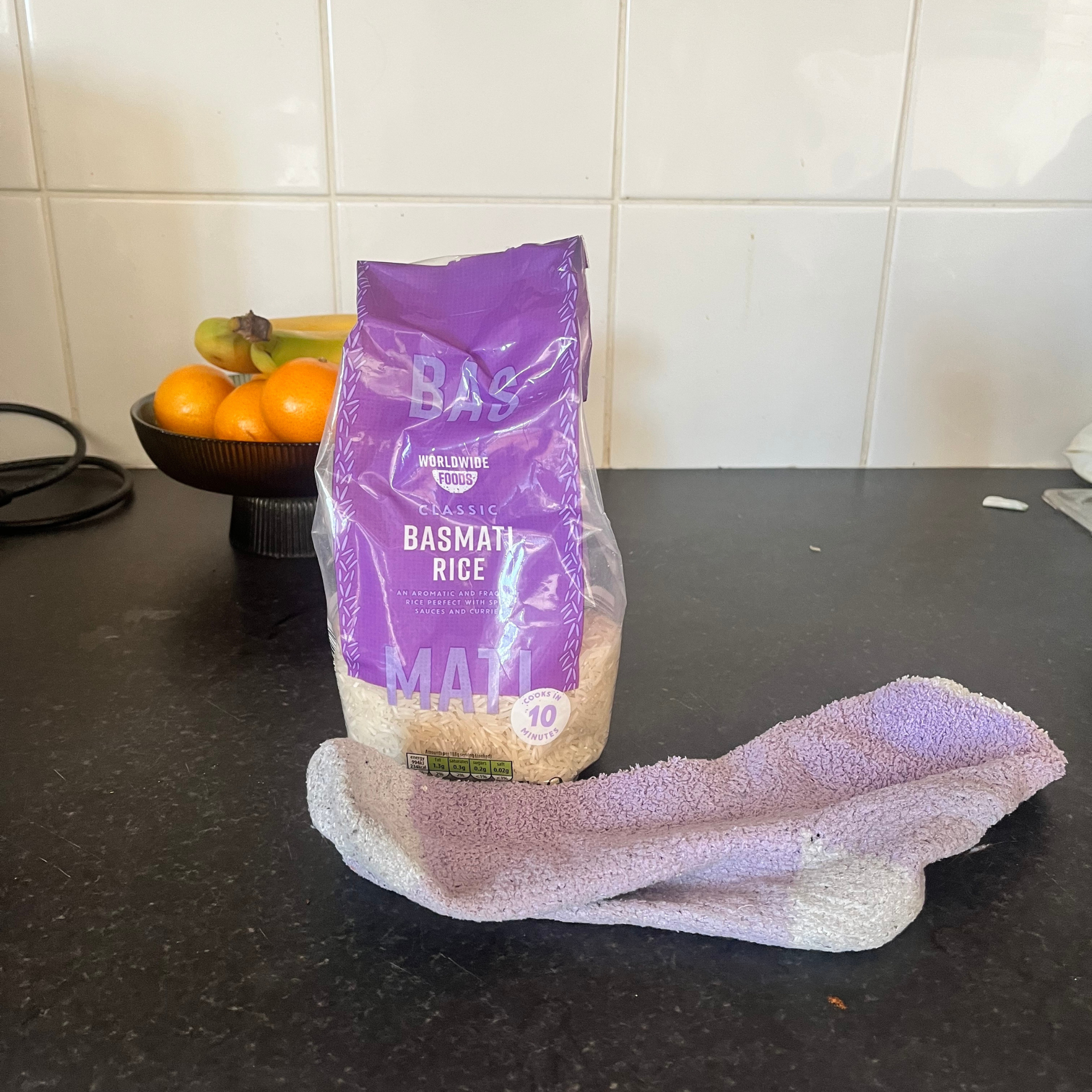 A purple sock and purple bag on rice on kitchen counter.