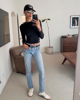L.A. woman takes a selfie in straight leg jeans, long sleeve t-shirt, a baseball cap and sunglasses