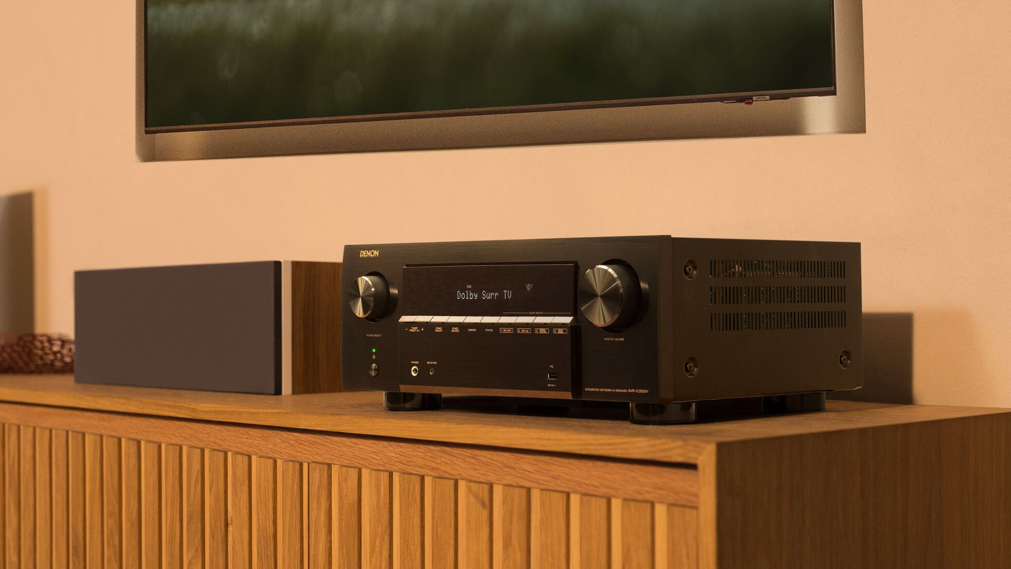 Denon AVR-X2900H on a side table next to a speaker
