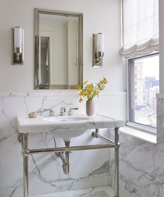 A bathroom with white and grey marble cladding on the lower half of the walls