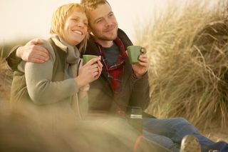 Couple drinking coffee on the beach.