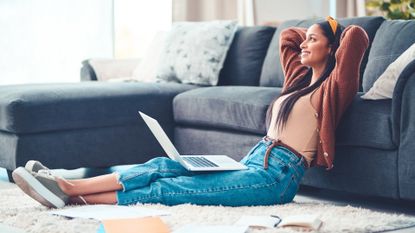 Shot of a young woman relaxing in the living room at home with her laptop and planning books open.