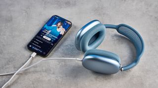 the apple airpods max 2 in blue photographed against a blue tom's guide background, showing the mesh headband, anodized aluminum ear cups, carry case, and controls