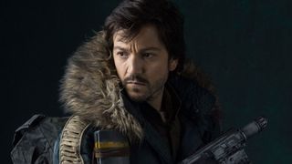 Cassian Andor, interpretado por Diego Luna, mira hacia atrás y tiene su arma preparada para la acción en Star Wars: Rogue One