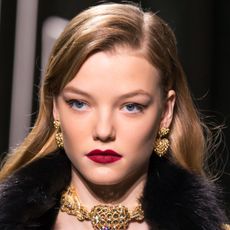 model on the runway wearing black eyeliner and dark red lipstick