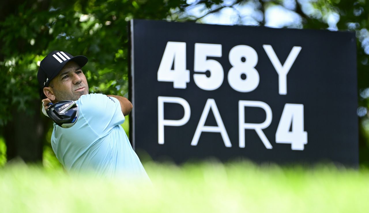 Garcia strikes his tee shot with a LIV Golf board in the background