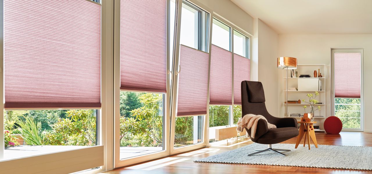 Pink blinds at patio doors in a living room. By Duette