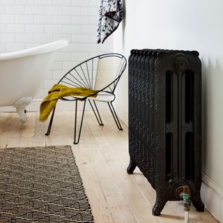 Black ornate cast iron radiator in a white bathroom