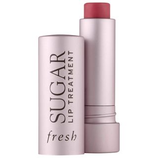 Open tube and lid of Fresh Sugar Lip Balm Hydrating Treatment on a white background