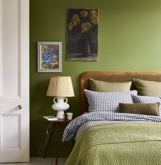 A green bedroom with wooden and cane bed headboard