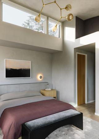 A bedroom with overhead windows, a muted color palette and bedside wall lights