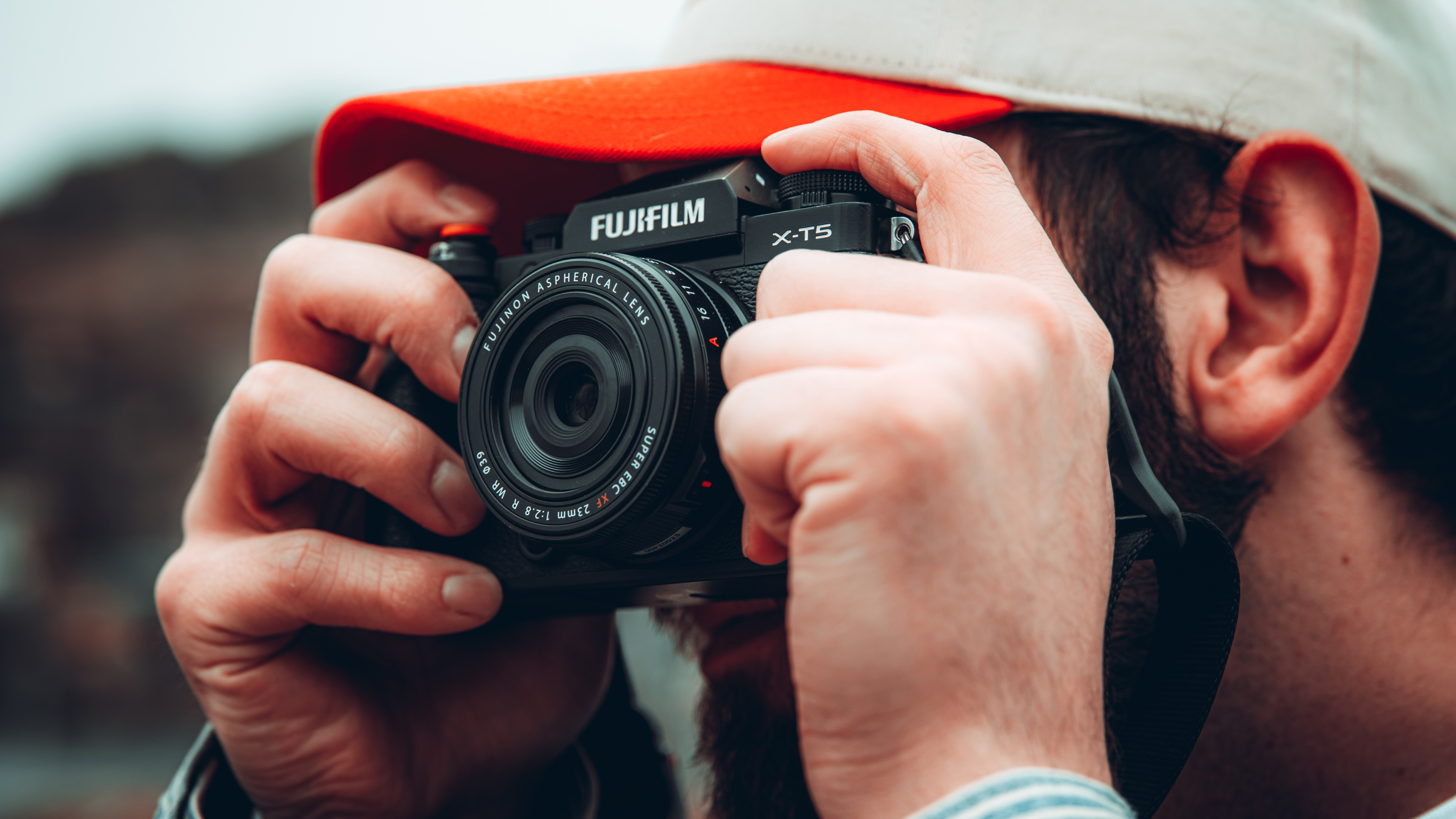 Fujifilm XF 23mm f/2.8 R WR lens attached to a Fujifilm X-T5 camera held up to a person&#039;s face